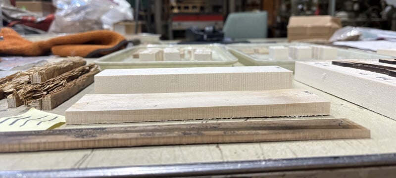 Manufactured low-lignan wood boards of various thickness and densities, sitting in samples on a table in a wood materials lab.
