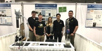 five people stand around a table at a conference