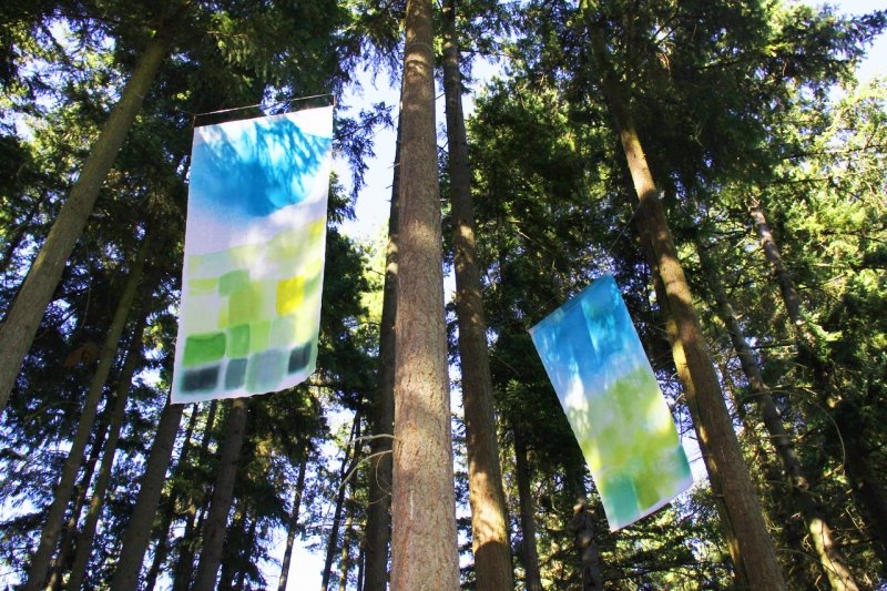 Panels of painted fabric hanging in the woods