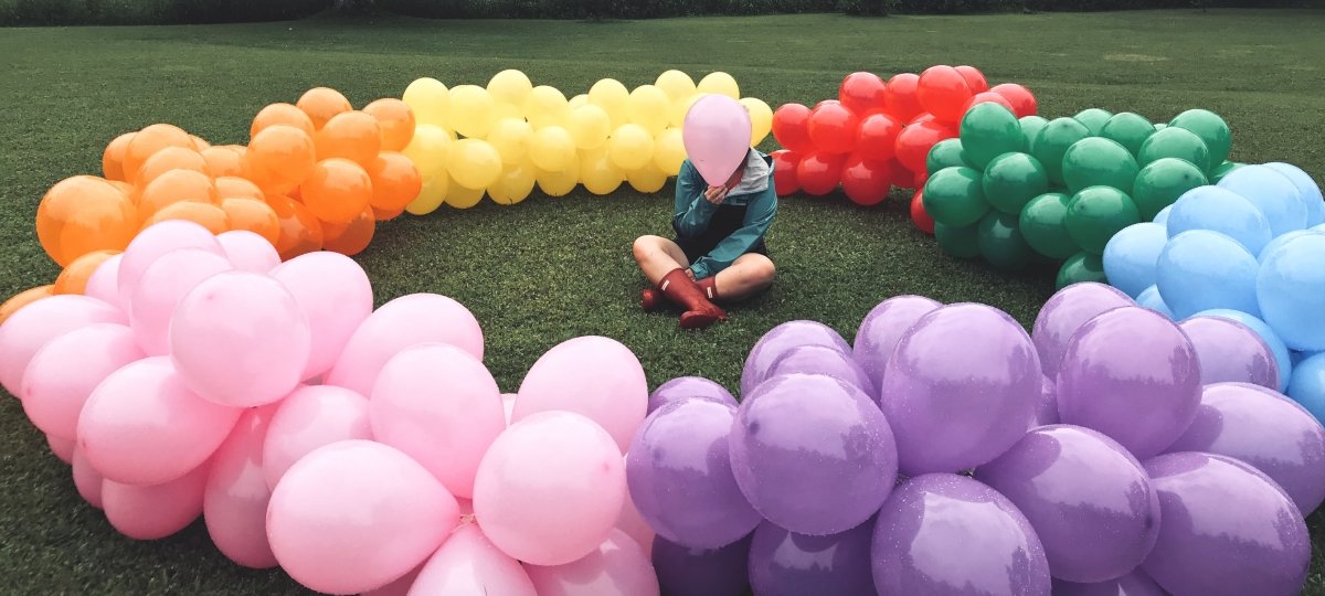 A circular balloon sculpture with individual sitting in center