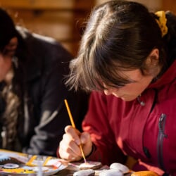 Students seated, painting stones
