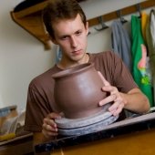 Student holding a large piece of pottery examining it.