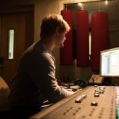 A student sitting at a control booth adjusing settings during a performance.