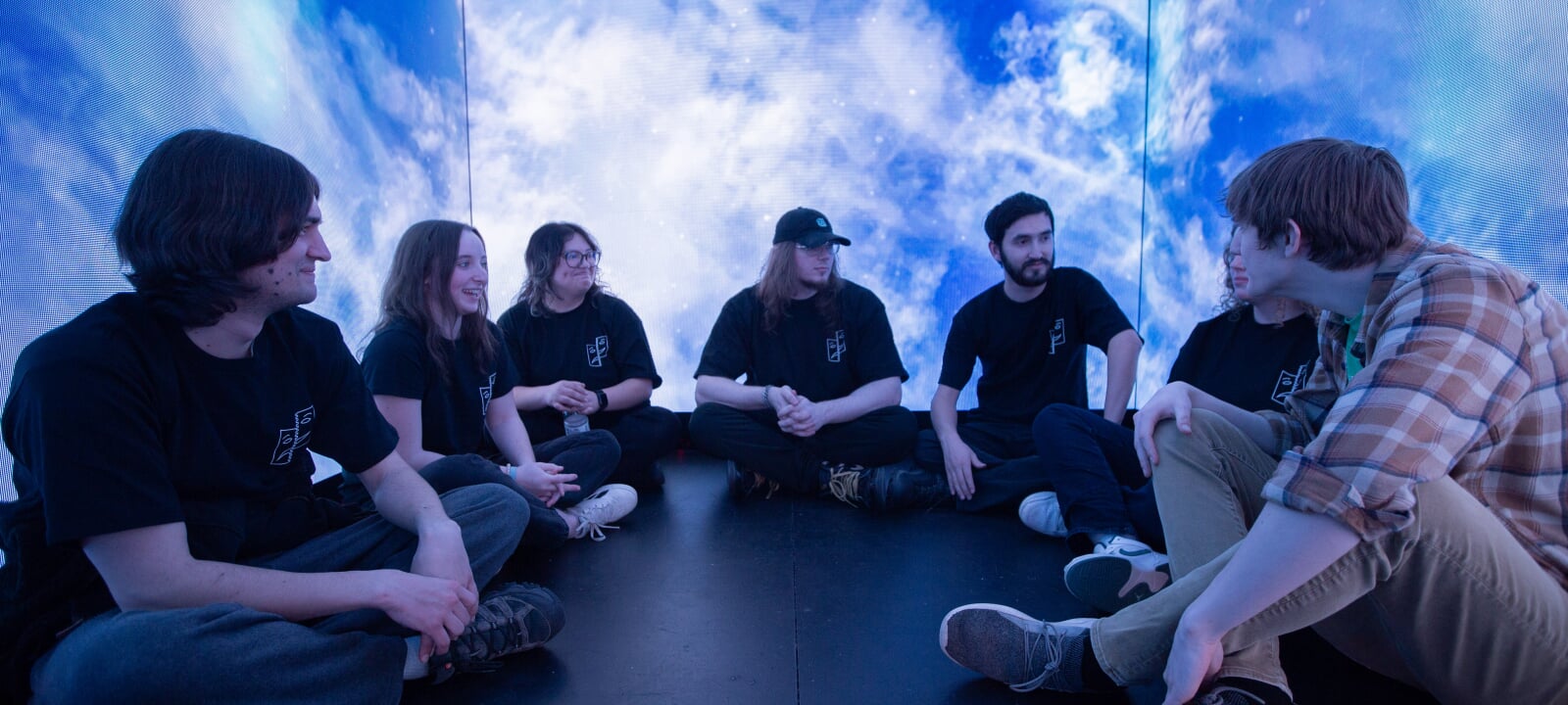 Students converse inside an LED wall cube