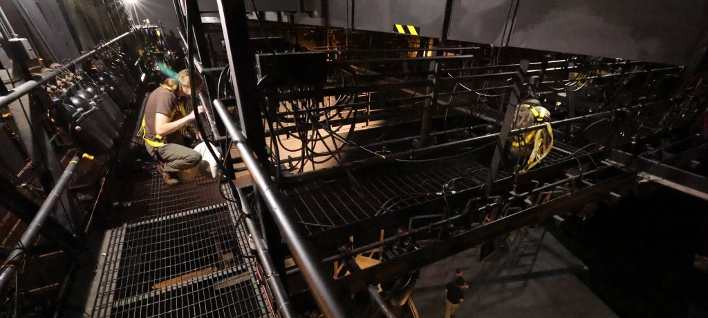 Student on a catwalk high in the rafters setting a cable