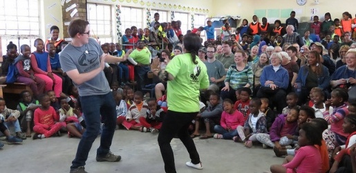 Concert Choir member dancing with a South African girl in front of a large group of onlookers.
