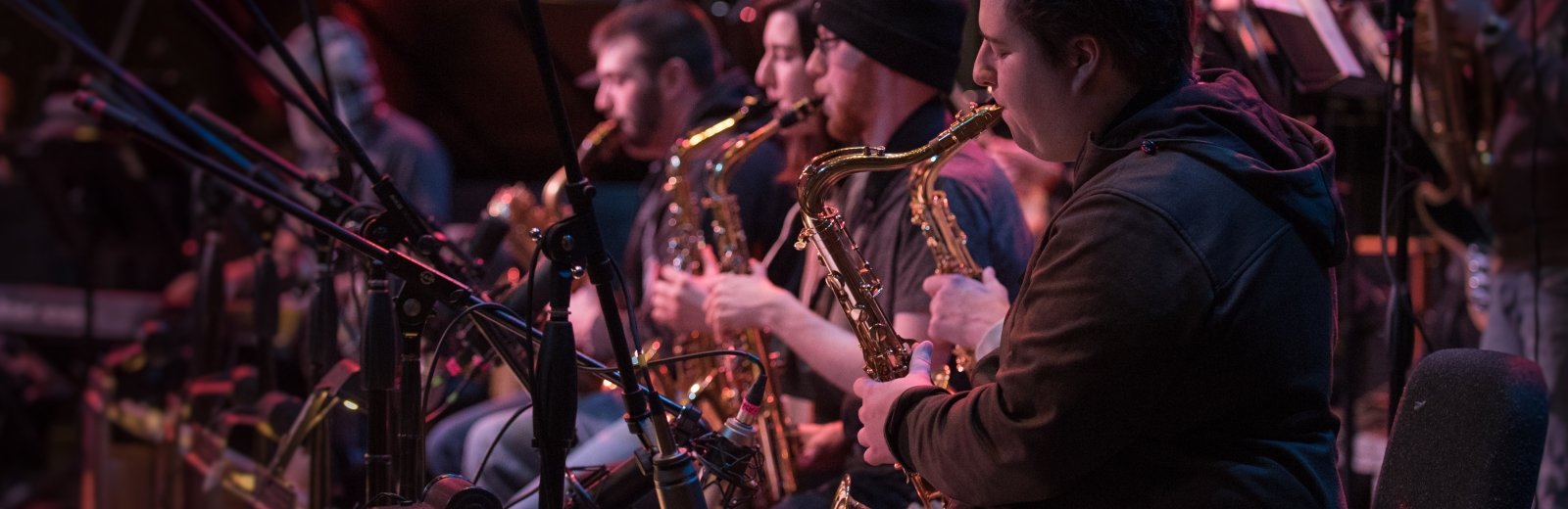 Students playing saxophones during a dress rehearsal of the Keweenaw Symphony Orchestra on the stage of the Rozsa Center for the Performing Arts.