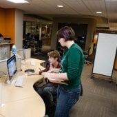 One student standing and another seated at a computer in the HDMZ.