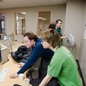 Students leaning on a desk looking at a computer screen in the HDMZ.