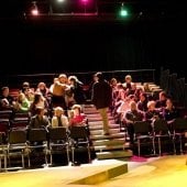 Students sitting in the audience seats of the McArdle Theatre discussing.