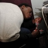 Student crouched down working on equipment under a table.