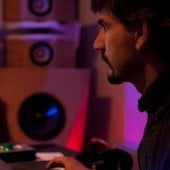 Student sitting at the computer inside the Recording Studio, adjusting controls