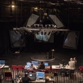 A view of the stage and the technical crew working with computers and sound equiptment.