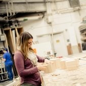 Student standing at a bench building wooden blocks.