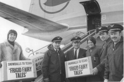 Four pilots, a stewardess and a man in a 1970s fur jacket hold boxes that say "Snowballs to Texas" Frigid Fairy Tales in front of a Republic Airlines plane with a blue goose logo on its wing.